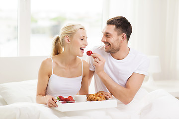 Image showing happy couple having breakfast in bed at home