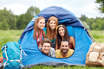 Image showing happy friends with backpacks in tent at camping