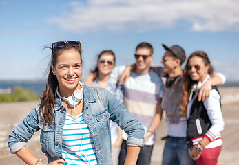 Image showing teenage girl with headphones and friends outside