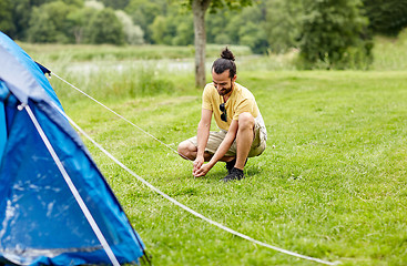 Image showing happy man setting up tent outdoors