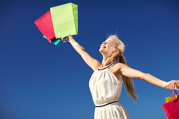 Image showing smiling woman with shopping bag rising hands