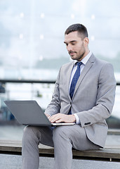 Image showing businessman working with laptop outdoors