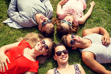 Image showing group of smiling friends lying on grass outdoors