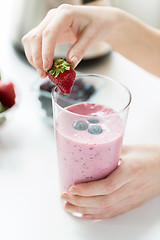 Image showing close up of woman with milkshake and strawberry