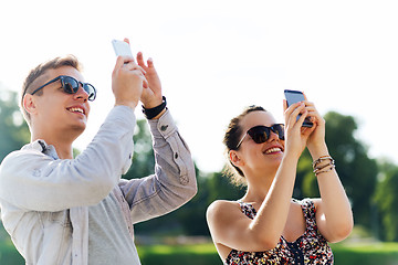 Image showing smiling friends with smartphone taking picture