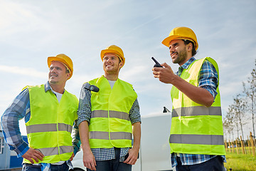 Image showing happy male builders in vests with walkie talkie