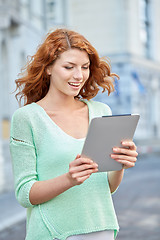 Image showing smiling teenage girl with tablet pc on city street