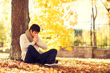 Image showing ill man with paper tissue in autumn park