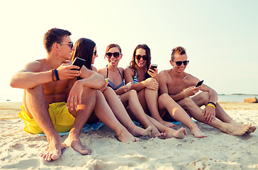 Image showing friends with smartphones on beach