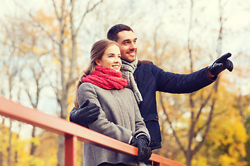 Image showing smiling couple hugging on bridge in autumn park