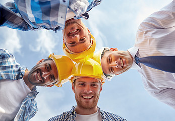 Image showing close up of builders wearing  hardhats in circle