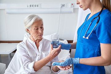 Image showing nurse giving medicine to senior woman at hospital