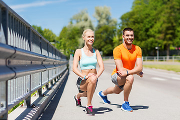 Image showing smiling couple stretching leg outdoors