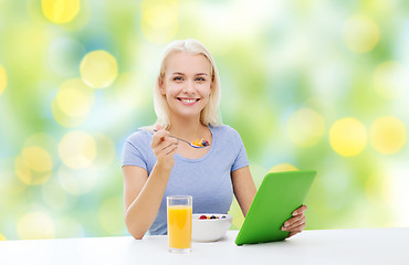 Image showing smiling woman with tablet pc eating breakfast