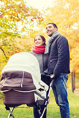 Image showing smiling couple with baby pram in autumn park