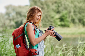 Image showing happy woman with backpack and camera outdoors