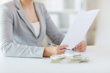 Image showing close up of female hands with money and tax report