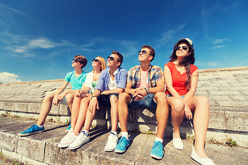 Image showing group of smiling friends sitting on city street