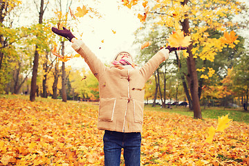 Image showing smiling little girl with autumn leaves in park