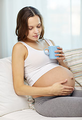 Image showing happy pregnant woman with cup drinking tea at home