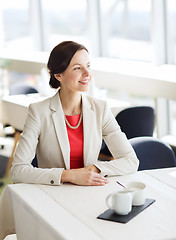 Image showing happy woman sitting at table in restaurant