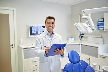 Image showing happy male dentist with clipboard at dental clinic