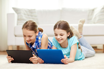 Image showing happy girls with tablet pc lying on floor at home