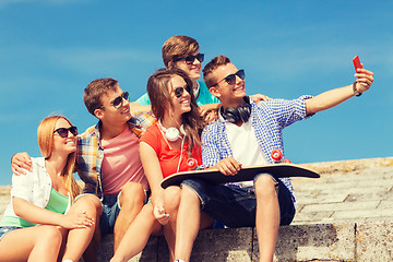 Image showing group of smiling friends with smartphone outdoors