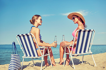 Image showing happy women sunbathing in lounges on beach