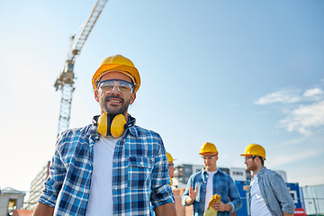 Image showing group of smiling builders in hardhats outdoors