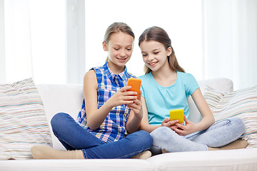 Image showing happy girls with smartphones sitting on sofa