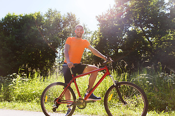 Image showing happy young man riding bicycle outdoors