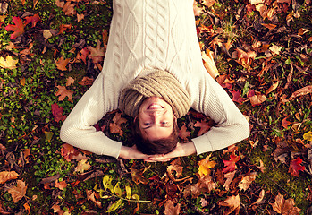 Image showing smiling young man lying on ground in autumn park