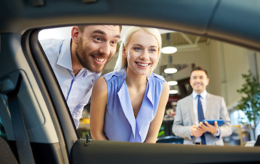 Image showing happy couple with car dealer in auto show or salon