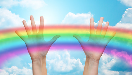 Image showing palms of human hands thumbs up over rainbow in sky