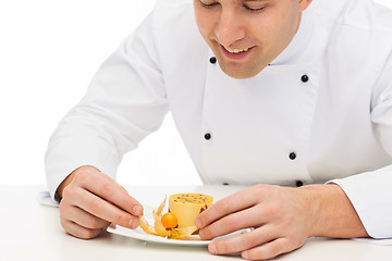 Image showing close up of happy male chef cook decorating dessert