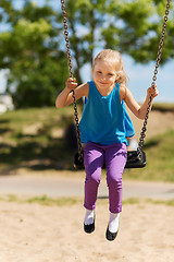 Image showing happy little girl swinging on swing at playground