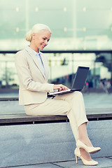 Image showing smiling businesswoman working with laptop outdoors