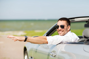 Image showing happy man driving cabriolet car and waving hand