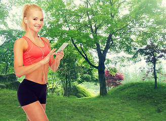 Image showing smiling sporty woman with smartphone and earphones