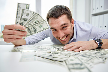 Image showing happy businessman with heap of money in office