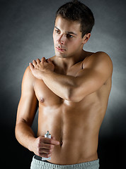 Image showing young male bodybuilder applying pain relief gel