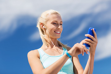 Image showing happy woman with smartphone and earphones outdoors