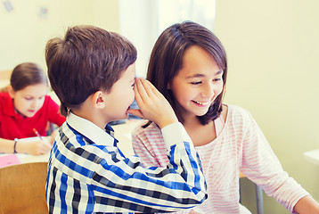 Image showing smiling schoolboy whispering to classmate ear