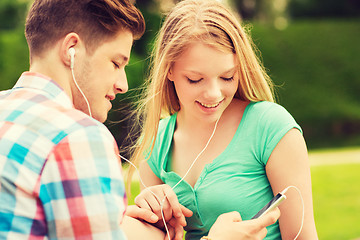 Image showing smiling couple with smartphone and earphones