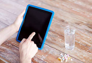 Image showing close up of hands with tablet pc, pills and water