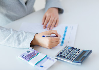 Image showing close up of hands counting money with calculator