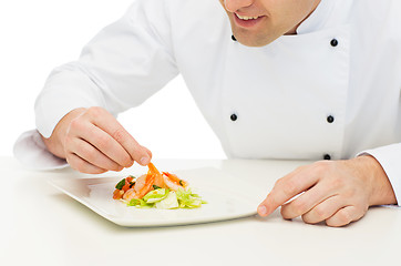 Image showing close up of happy male chef cook decorating dish