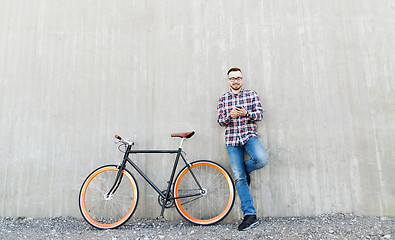 Image showing hipster man in earphones with smartphone and bike