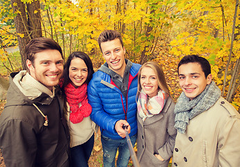 Image showing smiling friends taking selfie in autumn park